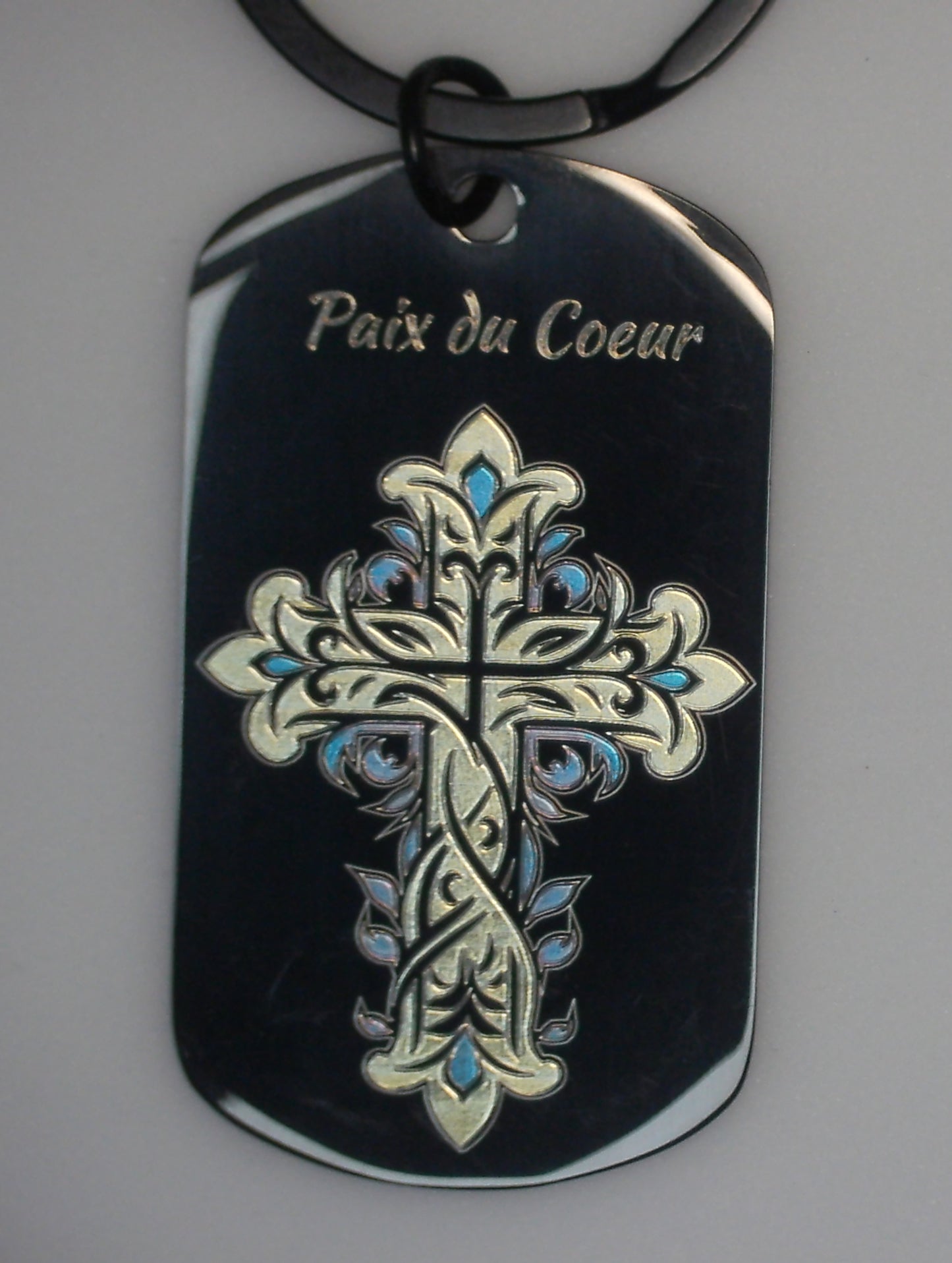gravure marquage couleur en or et bleu d'une croix avec ses joyaux bleu sur un porte cles en acier inoxydable noir