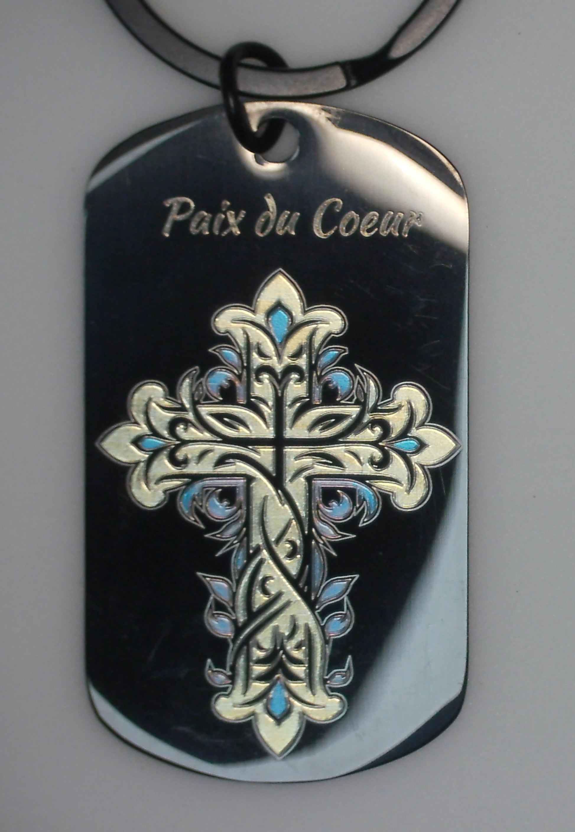 gravure marquage couleur en or et bleu d'une croix avec ses joyaux bleu sur un porte cles en acier inoxydable noir