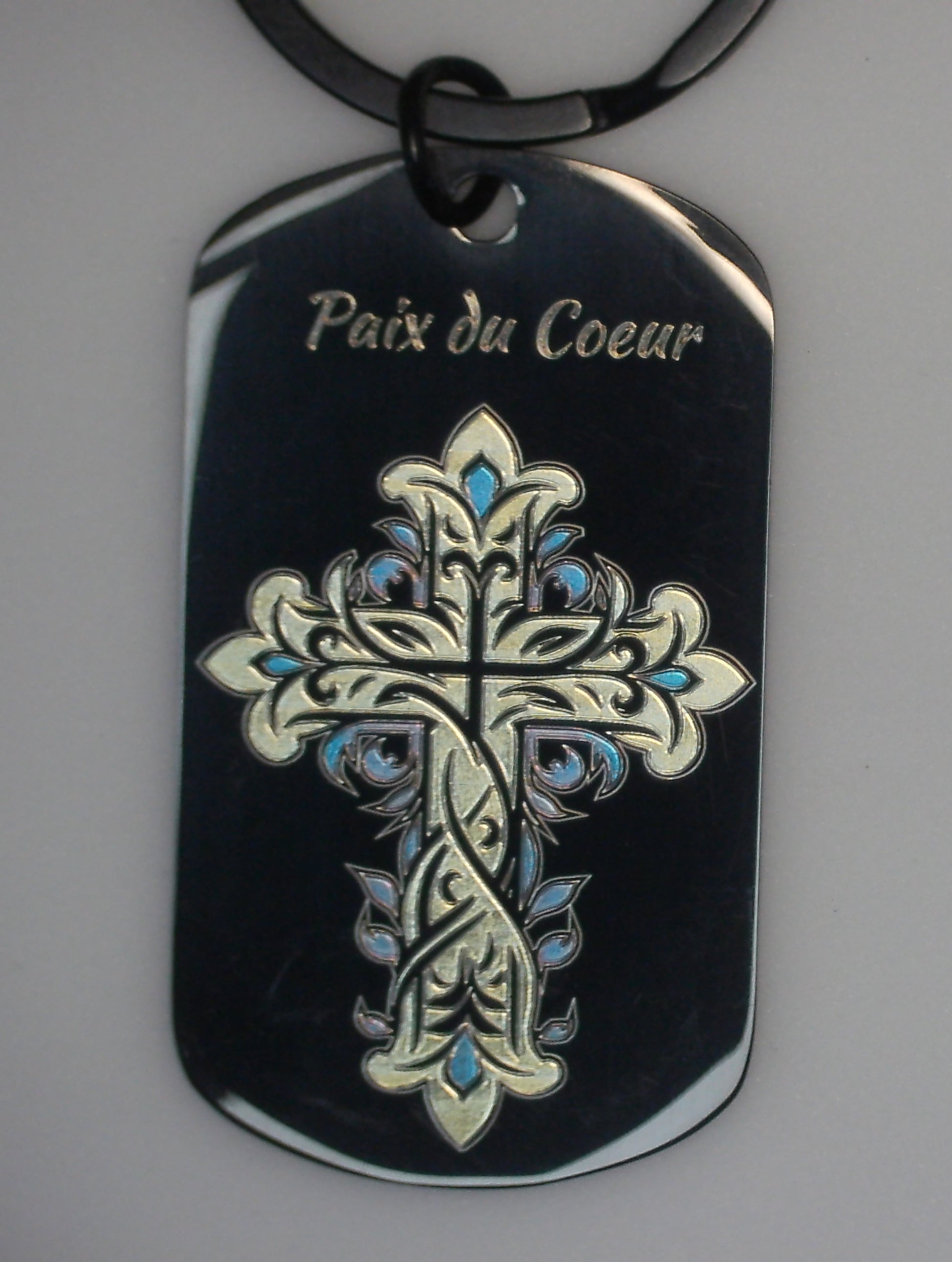gravure marquage couleur en or et bleu d'une croix avec ses joyaux bleu sur un porte cles en acier inoxydable noir